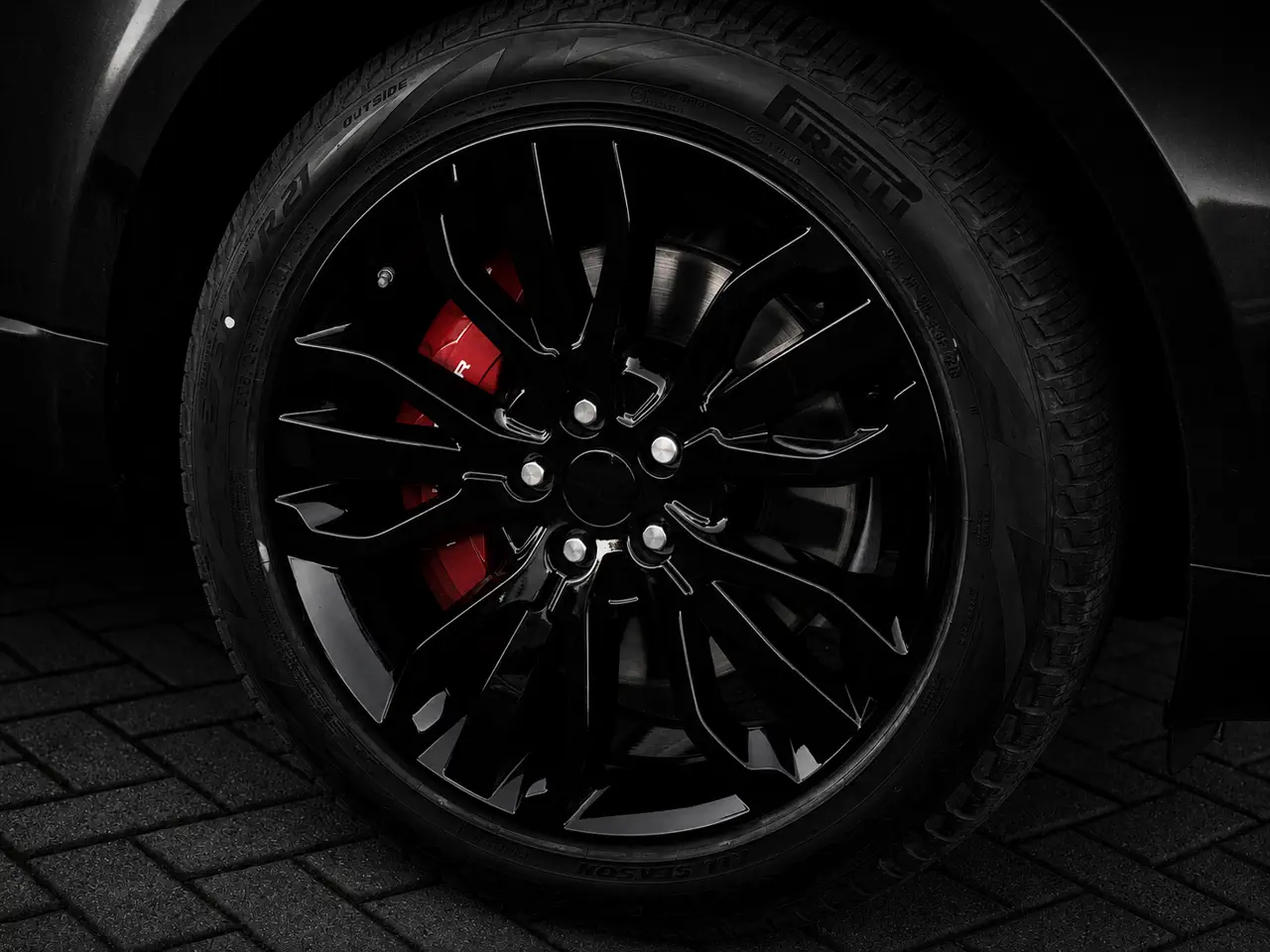 Refurbished gloss black alloy wheels with red brake calipers on a Range Rover, Stone